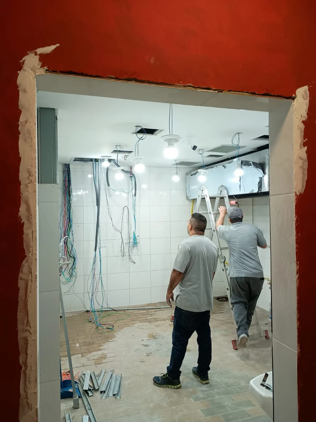 Equipe da VH Instalações executando obra comercial em shopping, vista pelo vão da entrada